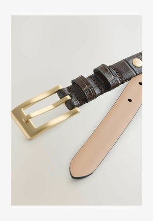 Cintura in pelle marrone scuro con finitura testurizzata, dotata di una fibbia in metallo dorato opaco e di un lato inferiore beige chiaro e liscio.