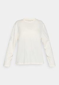 Long-sleeve cream-colored t-shirt made of soft cotton. Features a crew neckline and minimalistic design with subtle logo detail on the front.