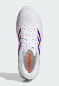 Λευκό αθλητικό παπούτσι με επάνω μέρος από δίχτυ, μπλε και πορτοκαλί λεπτομέρειες, στρογγυλή μύτη, επίπεδη σόλα και την ένδειξη "SUPERNOVA" τυπωμένη στην εσωτερική σόλα.