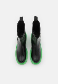 Czarne skórzane botki za kostkę o gładkim wykończeniu i zielonych gumowych podeszwach. Wśród cech znajdują się elastyczne boczne panele oraz pętle ułatwiające zakładanie.