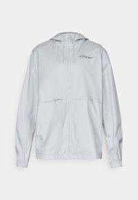 Veste à capuche zippée grise claire avec des poignets élastiques, des cordons de serrage et de petits logos "BARCA" et swoosh de Nike sur la poitrine gauche.