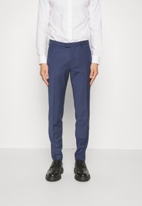 Navy blue tailored trousers with a smooth texture, featuring a slim fit, flat front, and belt loops, paired with black lace-up shoes.