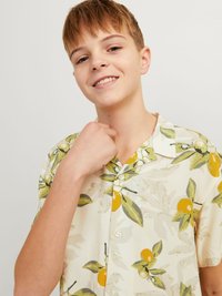 Camicia a maniche corte con colletto di colore crema, decorata da un motivo di foglie arancioni e verdi; tessuto leggero con bottoni, che presenta una vestibilità rilassata.