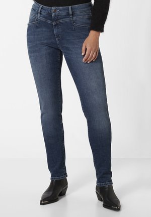 Denim-Jeans in einem mittelblauen Waschung mit schmaler Passform. Zu den Merkmalen gehören eine klassische Knopfverschlus, frontale Taschen und dezente Stichdetails.