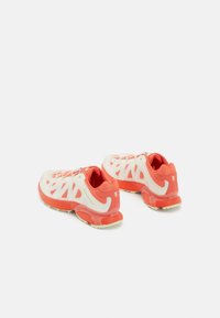 Red and white athletic shoes with a textured mesh upper, lightweight design, and rubber soles. Features a lace-up closure and logo accents.