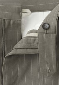 Pantalon gris à fines rayures avec braguette zippée, fermeture par bouton et taille partiellement ouverte.