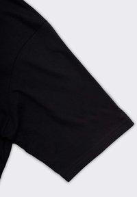 Maglietta nera a maniche corte con una morbida texture in cotone. Presenta un collo rotondo e cuciture lisce. Il design è semplice e privo di decorazioni.