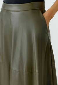 Jupe en cuir vert olive au toucher lisse, dotée d'une ceinture large, de détails de couture subtils et de poches latérales pour plus de fonctionnalité.