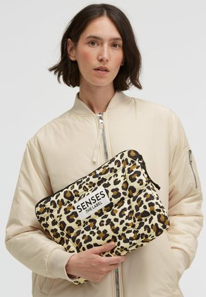 Gesteppte Clutch mit Leopardenmuster und weißem Logo-Patch, ausgestattet mit einem Reißverschluss. Das Material ist weich mit einer glänzenden Oberfläche, vorwiegend beige und braun.