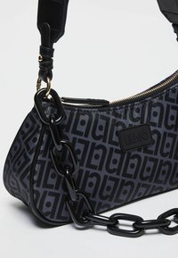 Borsa a spalla nera con motivo, dalla forma curvata, con una tracolla lucida a catena e chiusura con zip, realizzata in materiale sintetico liscio.