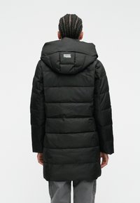 Sort pufferjakke med hætte, kviltet design og lange ærmer. Bagsiden har et patch-label og en glat tekstur.