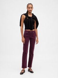 Débardeur noir ajusté, pantalon évasé en velours côtelé bordeaux, et ballerines noires. Pull posé sur les épaules. Texture lisse, design décontracté.