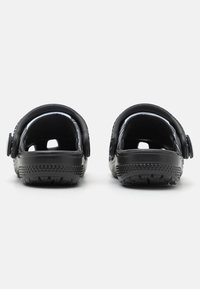 Black plastic sandals with back straps, open toe design, textured sole for grip, and adjustable side fastenings.
