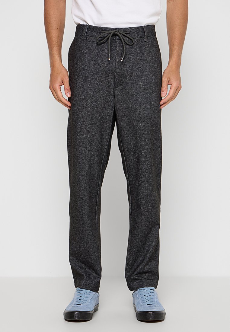 Graue Jogginghose aus weichem Material, mit elastischem Bund und Kordelzug, seitlichen Taschen und schmal zulaufenden Beinen. Geeignet für Freizeitoutfits.