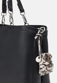 Sac à main en cuir noir à surface texturée, avec ferrures argentées, double anse et accessoire amovible à motif.