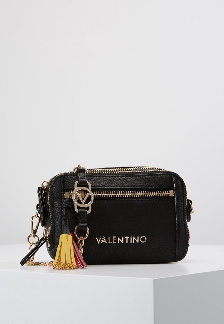 Černá kožená crossbody taška se zlatými detaily, zipovými prvky, embosovaným logem a barevným třásněm v růžové, žluté a červené barvě.