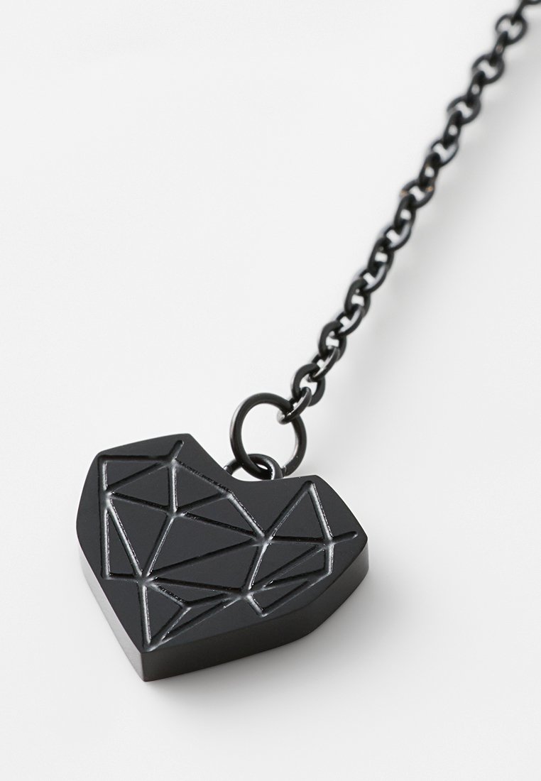 Czarny geometryczny wisiorek w kształcie serca z fasetowanym wzorem, zawieszony na czarnym łańcuszku. Gładka tekstura z kanciastymi wzorami w całej powierzchni.