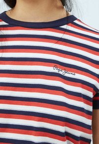 Stribet t-shirt med røde, hvide og marineblå vandrette striber. Har en rund halsudskæring og et lille "Pepe Jeans" logo på brystet.
