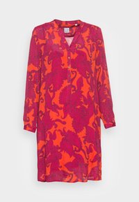 Abito a maniche lunghe in tessuto arancione vivace con un motivo paisley di colore rosa scuro. Presenta un collo a V e una chiusura a bottoni sul colletto.