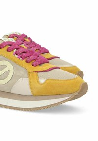 Baskets avec un design jaune et beige, présentant un mélange de matériaux en daim et en mesh, des lacets roses et une semelle en caoutchouc texturée.