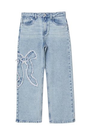 Jean en denim bleu clair avec un patch en forme de nœud effiloché sur la cuisse gauche, poches avant et fermeture par bouton.
