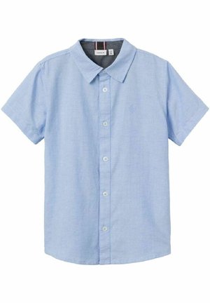 Camisa de manga corta azul claro con botones, cuello clásico y un sutil logo bordado en el pecho izquierdo.
