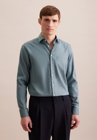 Lichtblauwe overhemden met lange mouwen, een zak op de borst en een gladde structuur, gecombineerd met donkere broek.