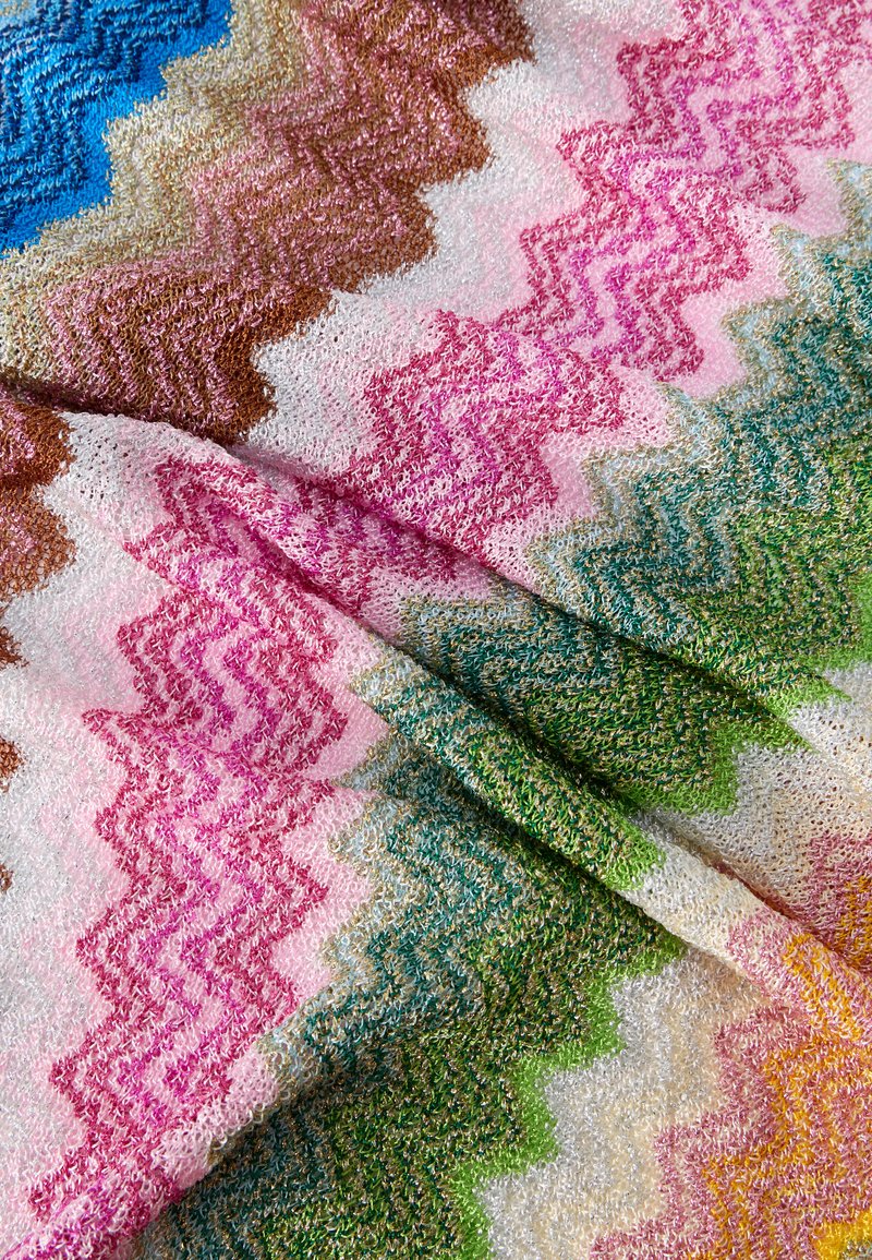 Tissu tricoté zigzag coloré avec des boucles texturées dans des nuances de rose, vert, marron, bleu et jaune, présenté en gros plan.