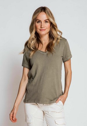 Olive green v-neck t-shirt with short sleeves, ribbed texture, and visible stitching details, paired with light cargo pants.