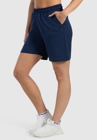 Pantaloni sportivi blu navy realizzati in materiale morbido, con vita elastica e tasche laterali, dal tessuto liscio e dalla vestibilità comoda.