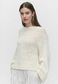 Wit gebreid sweater met een gestructureerde afwerking, ronde halslijn en verlaagde schouders. Ribgebreide zoom en manchet. Lichtgewicht en losvallend model.