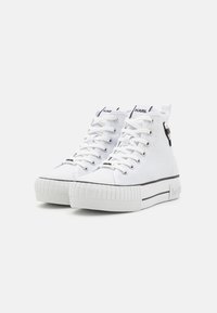 Białe sneakersy typu high-top na płaskiej, teksturowanej gumowej podeszwie, z czarnymi akcentami oraz logo na języku i boku.
