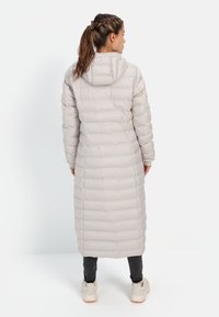Lichtgewicht beige pufferjack met capuchon, met een horizontaal doorgestikt patroon, lange lengte en ritsluiting. Geschikt voor koude weersomstandigheden.