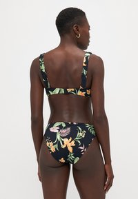 Bikini floreale in tessuto scuro. Presenta grandi motivi floreali verdi e arancioni, spalline regolabili e chiusura posteriore con gancio.