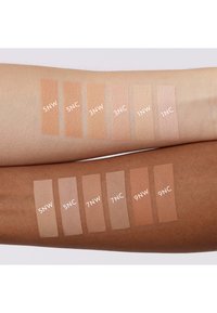 Nuances de fond de teint sur deux bras : peau claire avec les teintes 1NW à 5NW, et peau plus foncée avec les teintes 5NW à 9NC. Texture légère, mate.