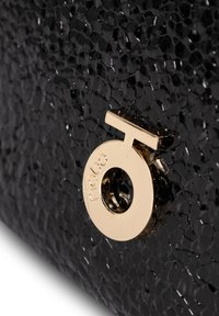 Borsa nera in tessuto con finitura lucida, hardware circolare in tonalità oro con dettaglio a intaglio e logo del marchio in rilievo.
