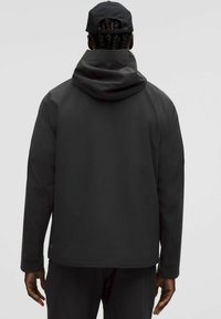 Čierna nepremokavá bunda s kapucňou, hladká textúra, mierne voľný strih a nastaviteľné manžety. Pohľad zozadu zobrazuje minimalizované dizajnové detaily.