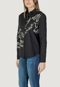 Camicia nera con bottoni, caratterizzata da design astratti in tonalità grigie, maniche lunghe, colletto e orlo curvo.