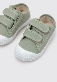 Baskets vertes pour tout-petits avec semelles et bouts en caoutchouc blanc, dotées de deux brides Velcro pour un ajustement facile.