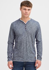 Duga rukava tamnoplava henley majica izrađena od teksturirane tkanine, s prednjim gumbima, kontrastnim bijelim ovratnikom i suptilnim heather uzorkom.