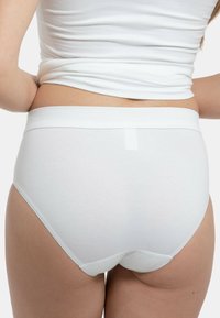 Weiße Baumwollslips mit glatter Textur, elastischem Bund und mittelhohem Schnitt, die ein einfaches und minimales Design aufweisen.