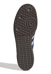 Adidas sneaker sole features a patterned dark rubber tread with circular and oval raised accents, and a branded logo near the heel.