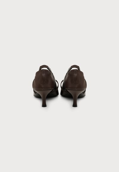 Paire de chaussures basses en cuir marron foncé vue de dos sur un fond clair uni.