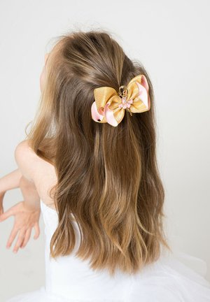 Girl with long light brown hair wearing a white outfit, hair partially pinned back with a pink and gold butterfly hair clip.