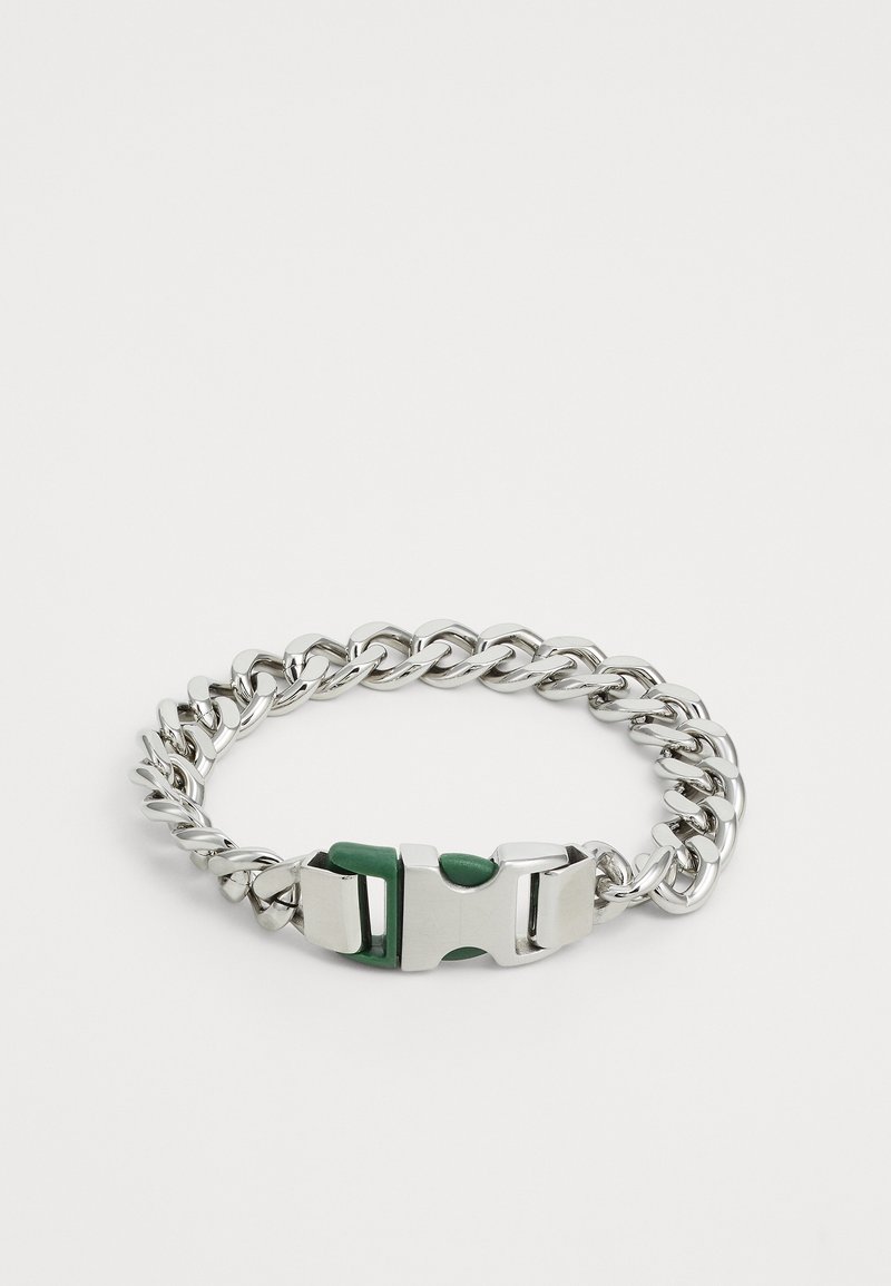 Bracciale in catena metallica con finitura argentata. Presenta una chiusura robusta con accenti verdi. I link sono spessi e interconnessi.