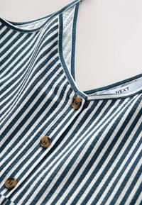 Haut rayé bleu marine et blanc, avec un col en V, six boutons, une texture douce, et une étiquette portant la mention "NEXT".