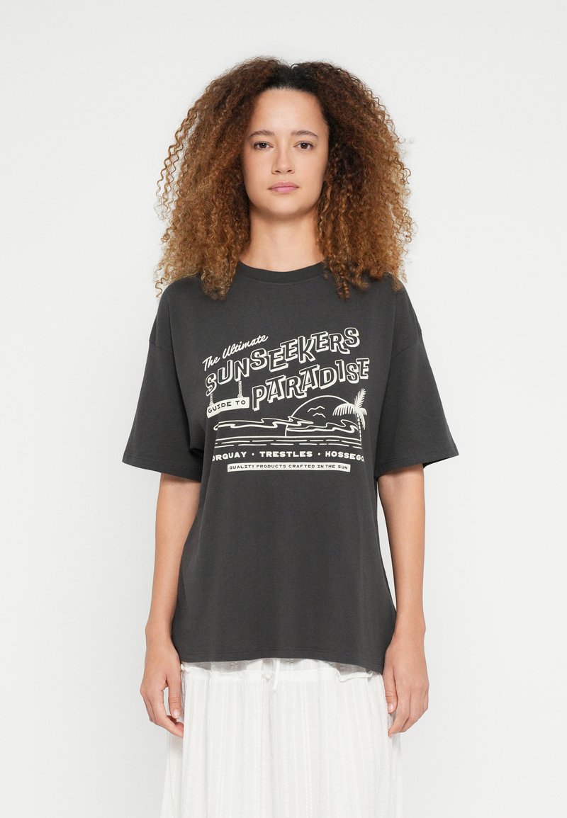 Mustast puuvillast graafiline t-särk, millel on valge trükitud tekst ja rannapilt. Lühikesed varrukad, avar lõige ja ümarlõikega kaelus.