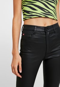 Svarta fusk läderbyxor med lätt glans, med en åtsittande design, framfickor och en liten röd logotagg.