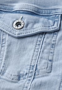 Light blue denim fabric with a stitched pocket flap secured by a metal button engraved with "STREET ONE."