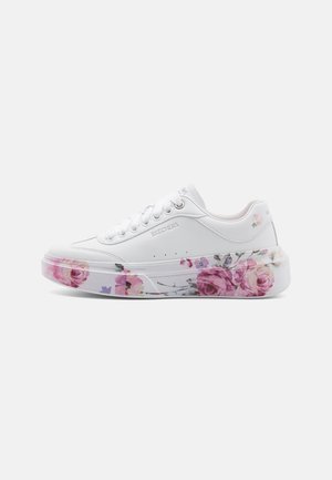 Hvid Skechers sneaker med pink og lilla blomsterprint på den gennemsigtige sål og lille blomsterdetalje nær hælen.